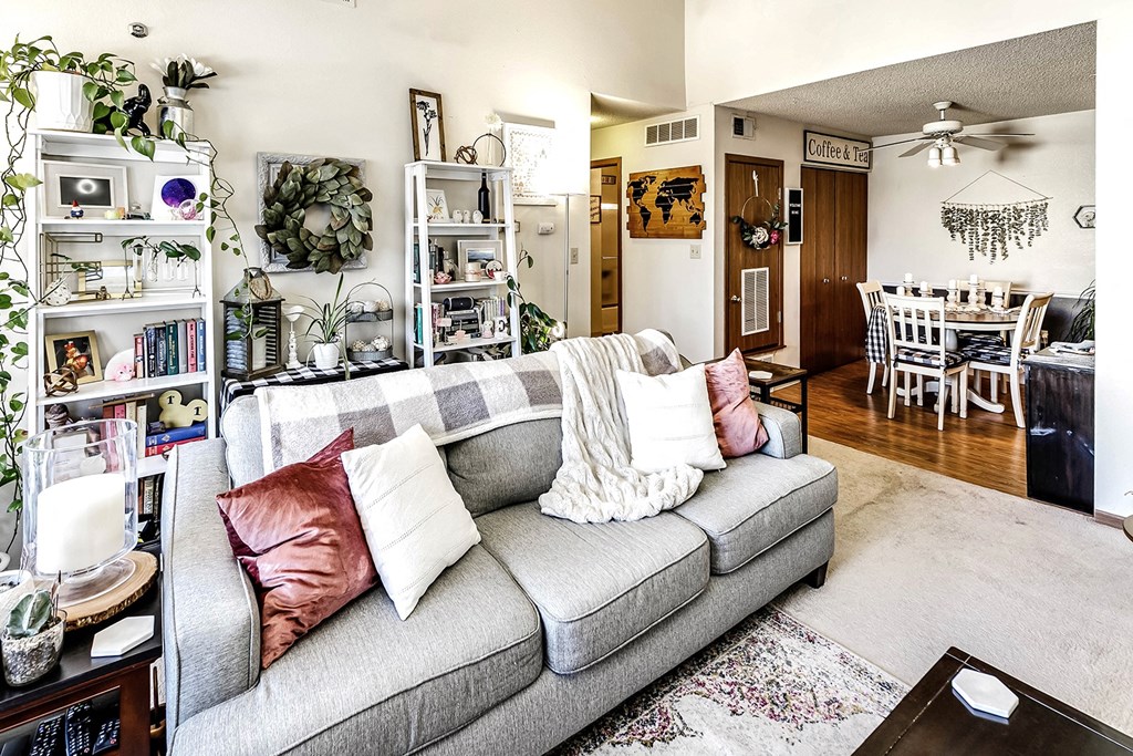 a living room with a gray couch and a dining room