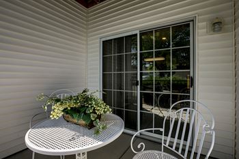 A white table with a plant on it sits on a porch.