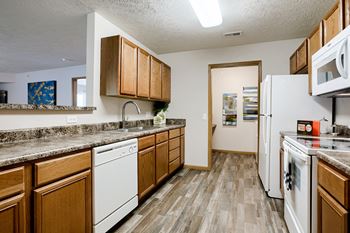 A kitchen with white appliances and wooden cabinets.
