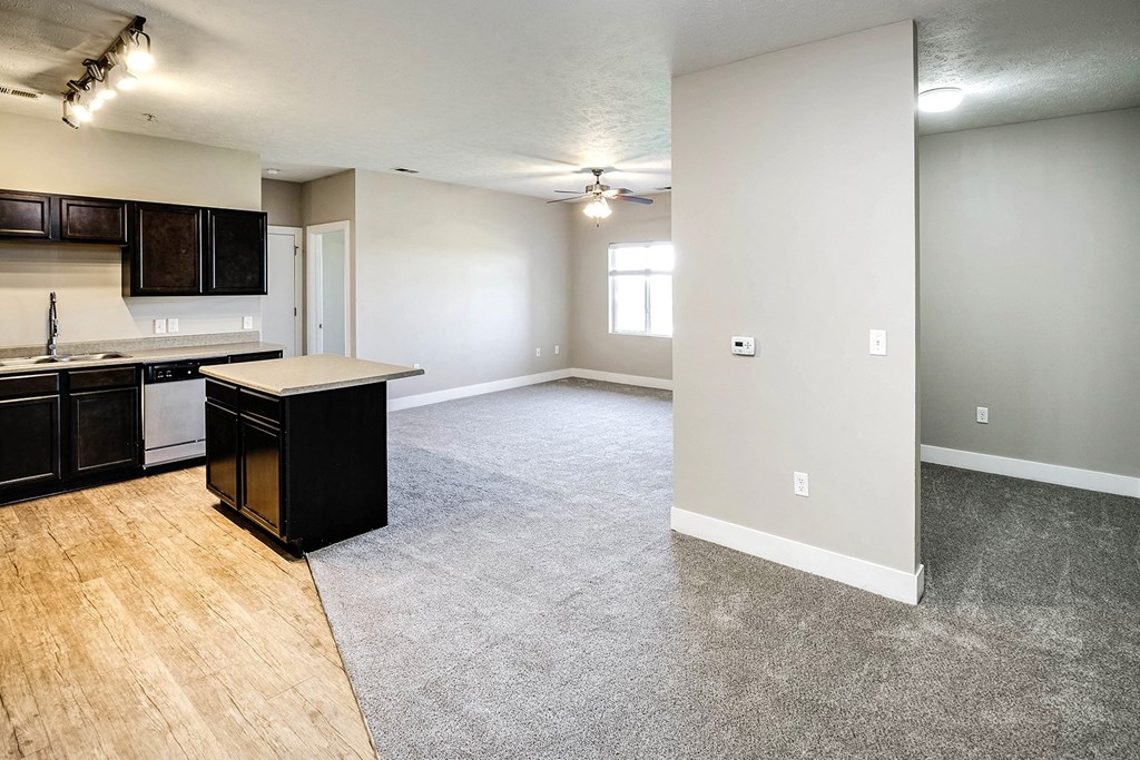 an empty living room with an empty kitchen with an island in the middle