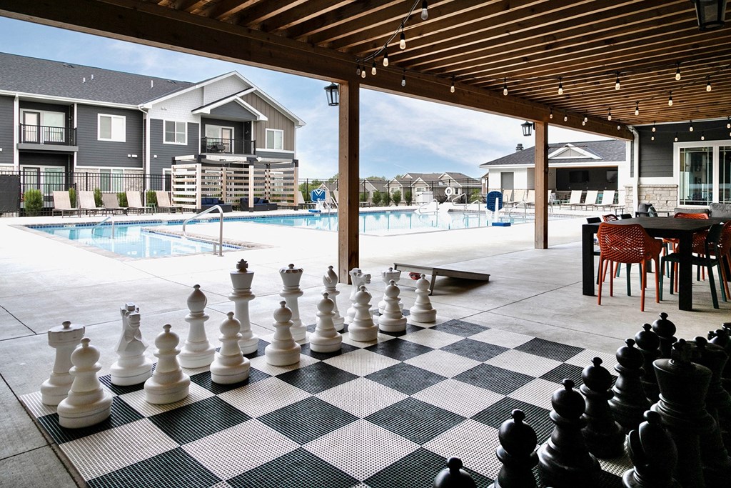 a large chess board in front of a swimming pool