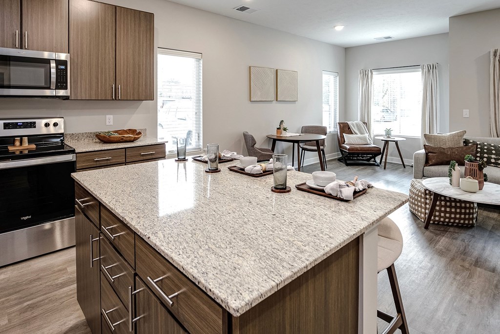 an open kitchen and living room with a large granite counter top