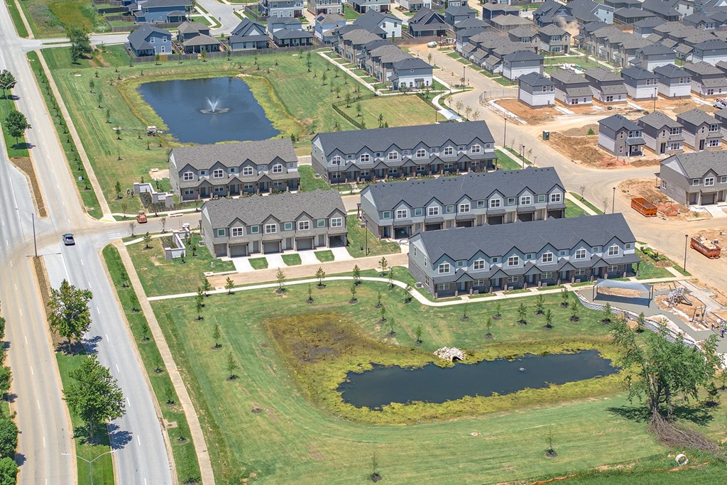 an aerial view of a neighborhood with houses and a pond in the middle
