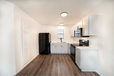 a kitchen with white cabinets and a black refrigerator