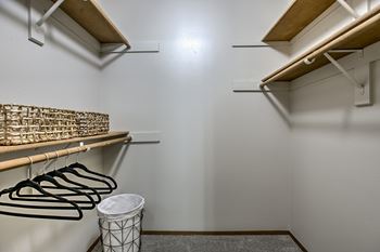 A white wall with a shelf and a trash can.