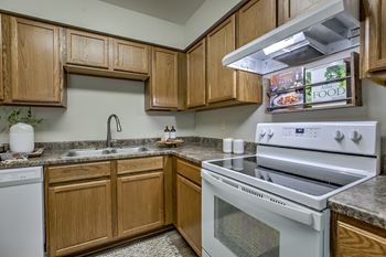 A kitchen with a white oven and wooden cabinets.