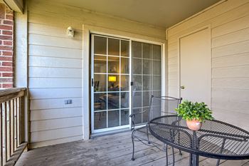 A balcony with a table and chairs and a potted plant.