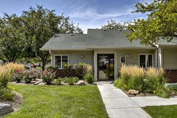 A house with a green lawn and trees in the background.