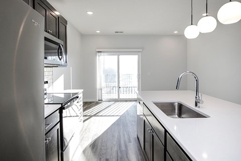 A modern kitchen with a stainless steel refrigerator and a sink with a faucet.