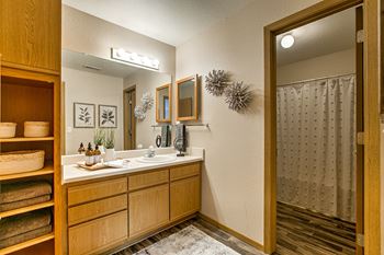 A bathroom with a wooden vanity and a mirror above it.