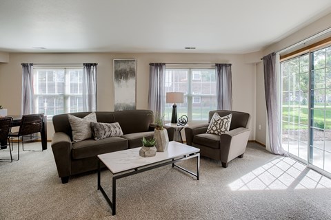 A living room with a grey couch, a white coffee table, and a dining table with chairs.
