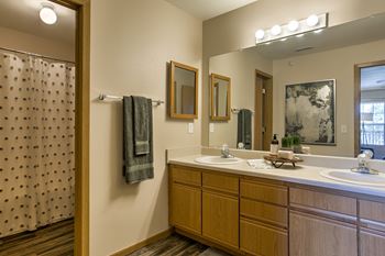 A bathroom with a shower curtain, two sinks, and a mirror.