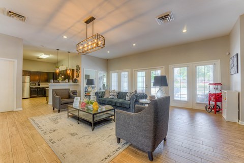 A spacious living room with a grey sofa and a glass coffee table.