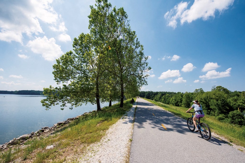 a person riding a bike on a road next to a lake