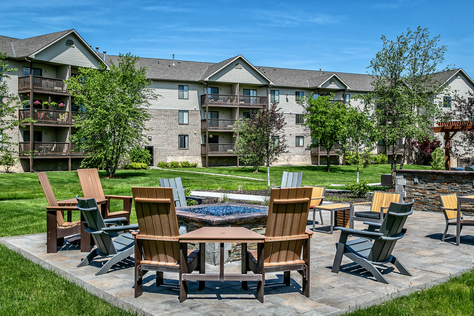 an outdoor patio with chairs and a fire pit in front of an apartment building