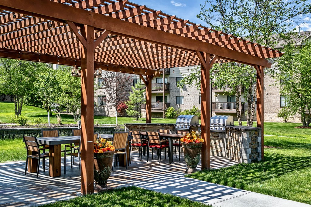 a patio with tables and chairs under a wooden pergola