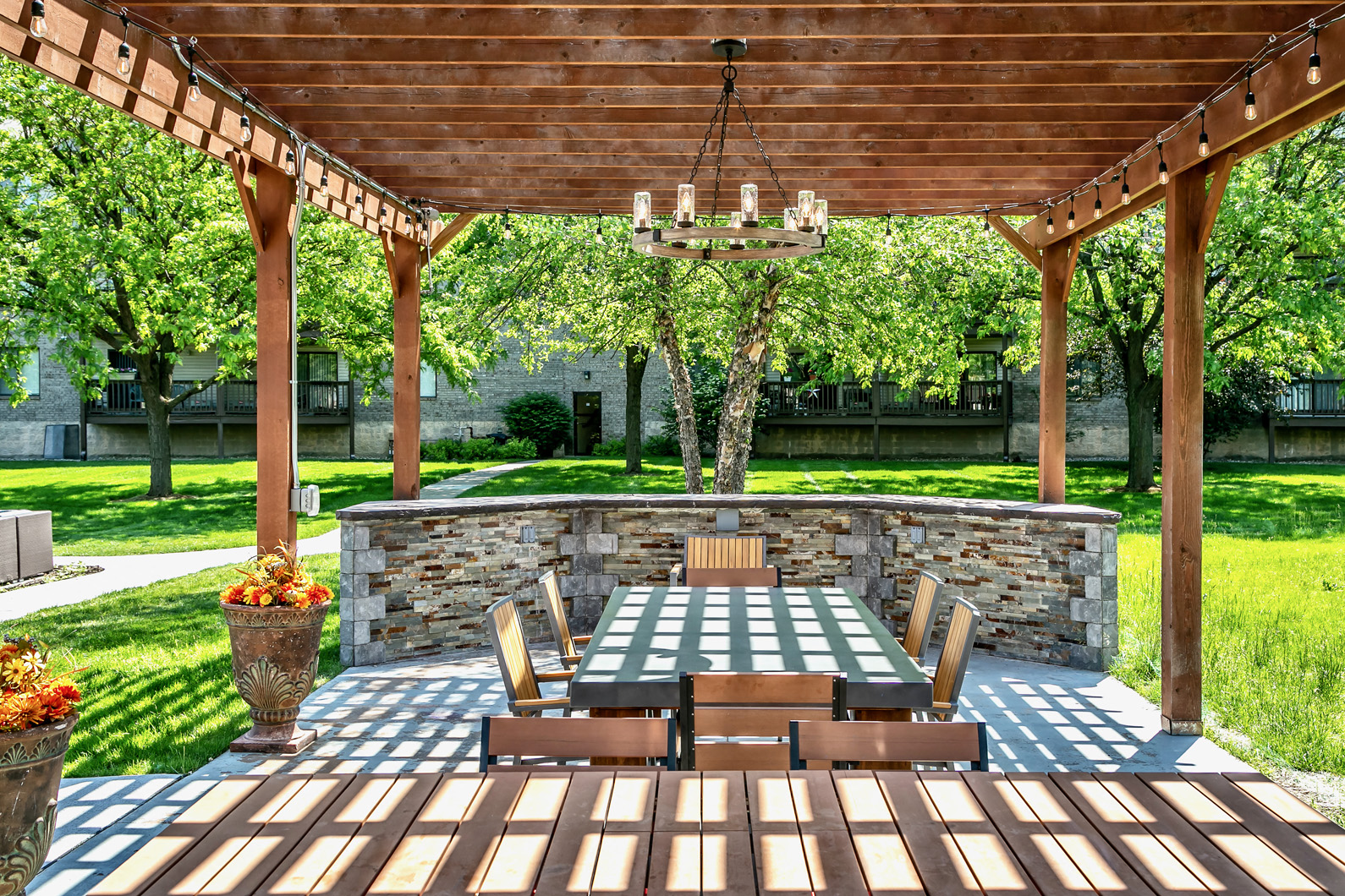 a patio with a table and chairs under a wooden pergola