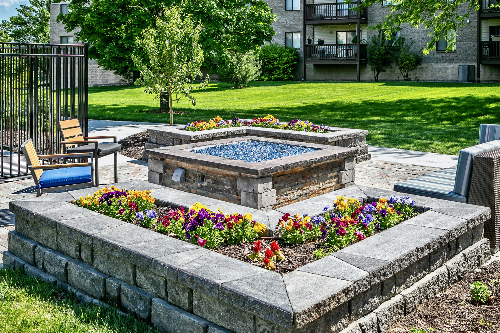 a stone retaining wall with a fountain in the middle of a garden