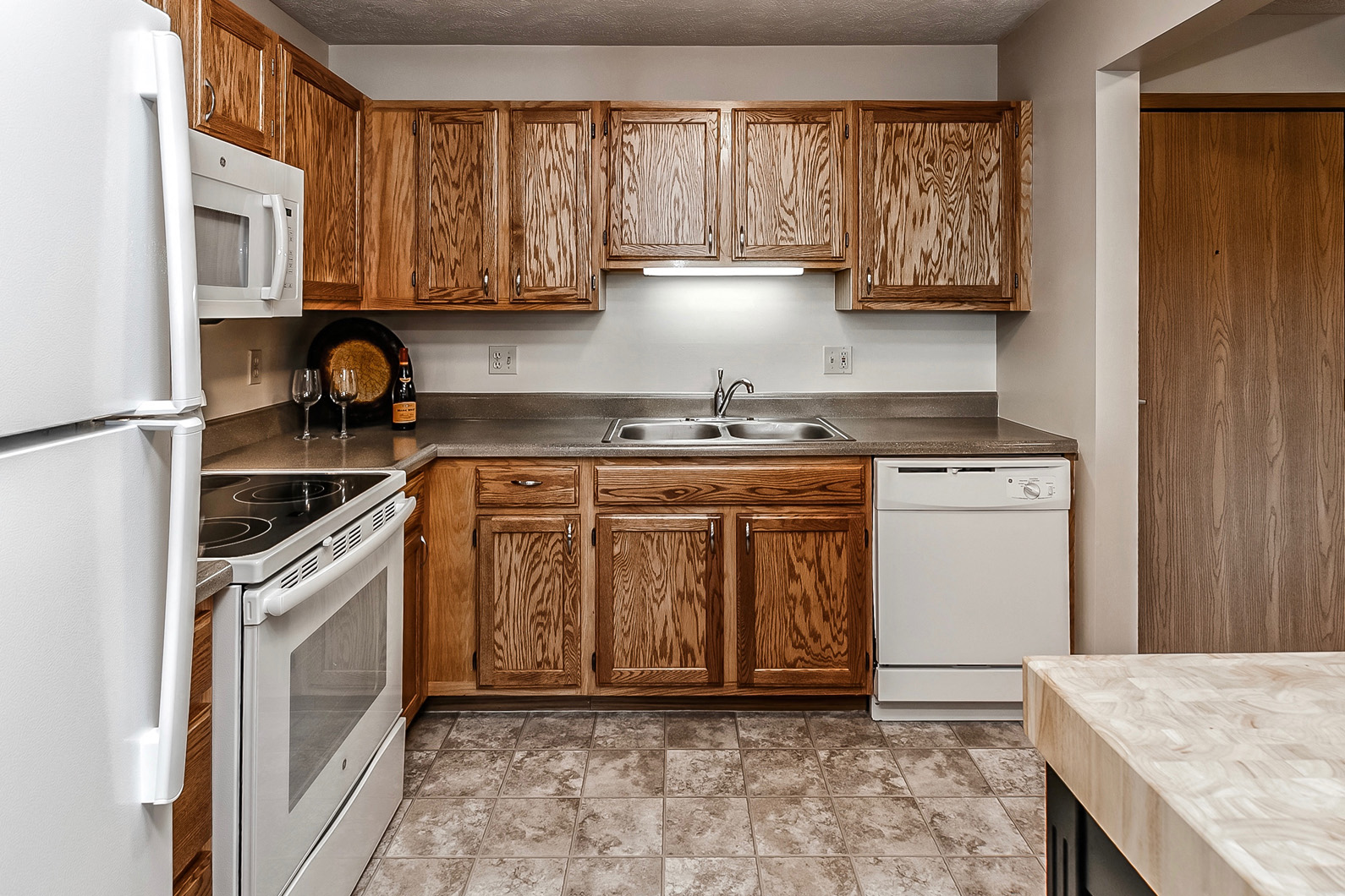 an empty kitchen with white appliances and wooden cabinets
