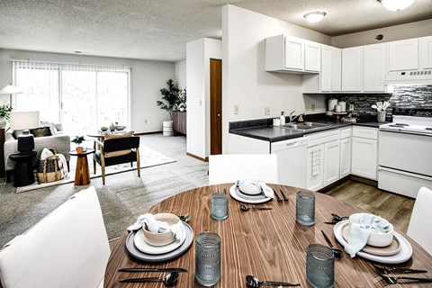 an open kitchen and living room with a wooden table