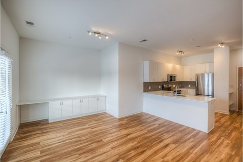 A kitchen with white cabinets and a wooden floor.