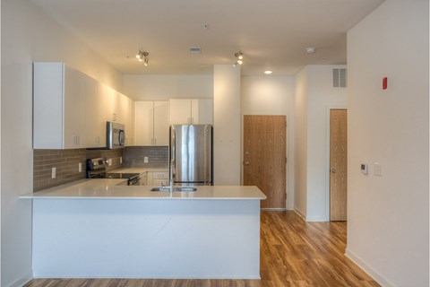A kitchen with a white counter and wooden floors.