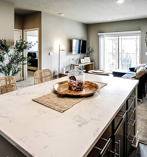 an open kitchen and living room with a marble counter top