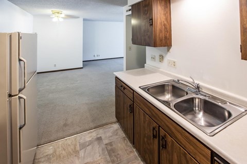 A kitchen with a refrigerator, sink, and cabinets.