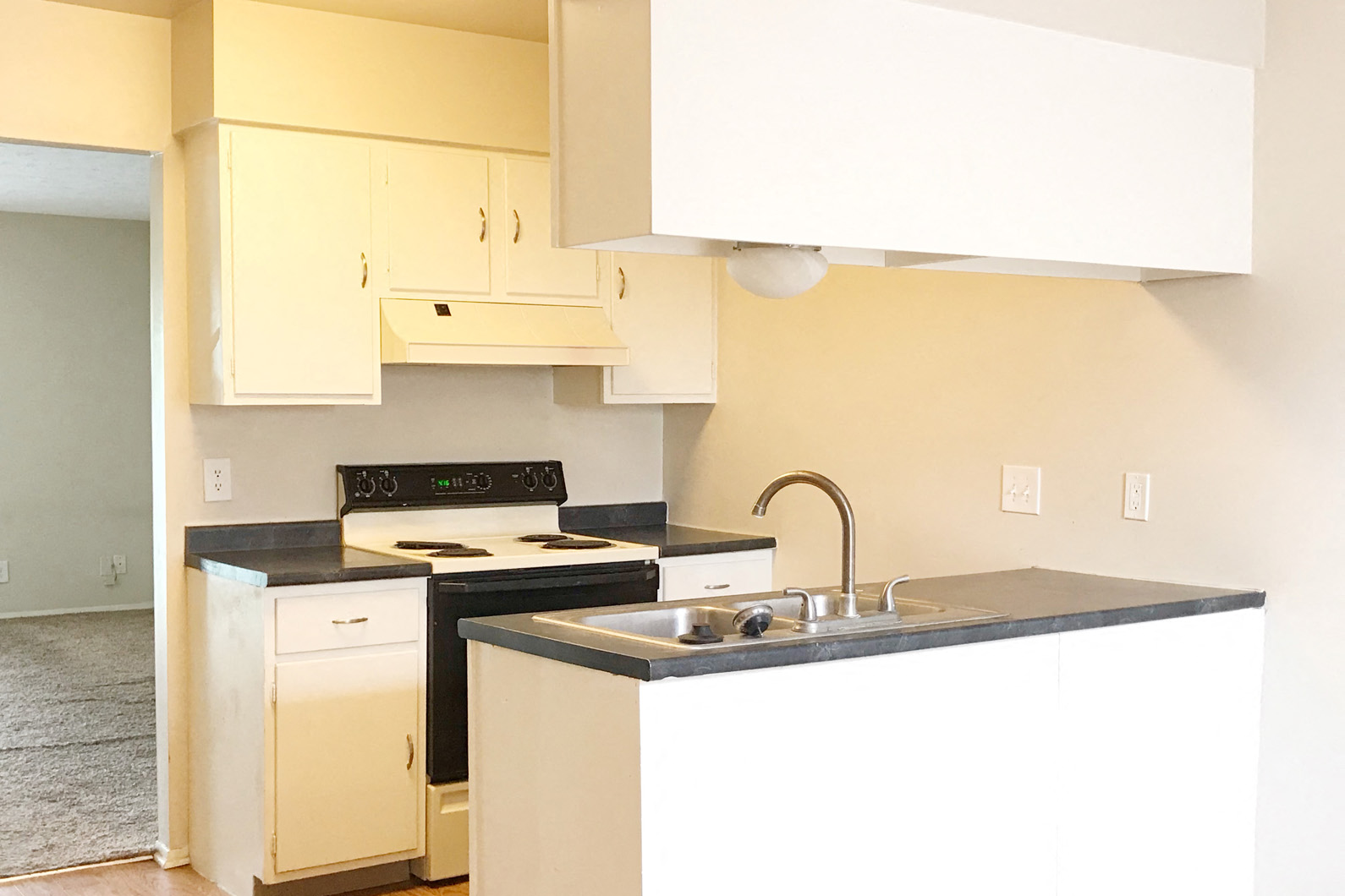 an empty kitchen with white cabinets and a sink