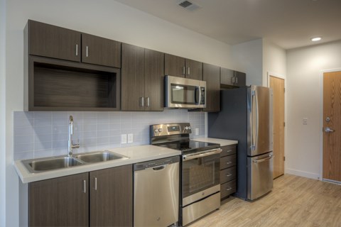 A modern kitchen with dark brown cabinets and stainless steel appliances.