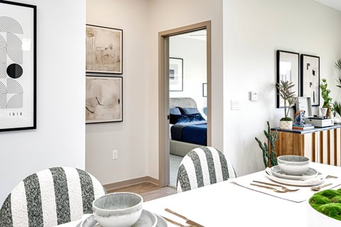 A dining room with a white table and striped chairs.