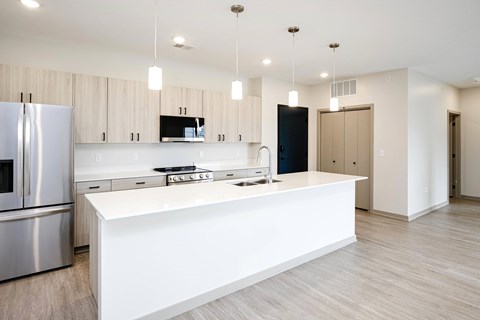 A modern kitchen with a white island and stainless steel appliances.