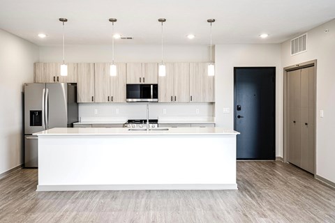 A modern kitchen with a white island and wooden flooring.