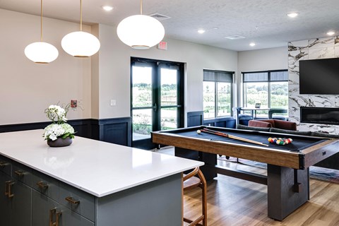 A pool table is in the middle of a room with a TV and a fireplace.