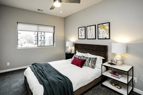 A bedroom with a bed, nightstand, and a window.