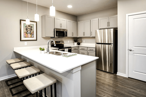 A kitchen with white countertops and stools.