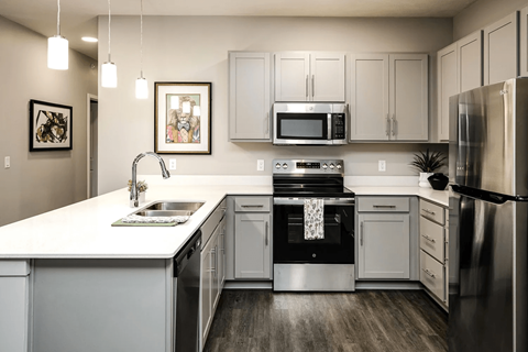 A modern kitchen with a white countertop and stainless steel appliances.