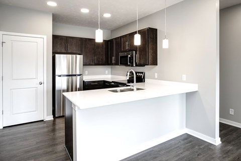 A kitchen with a white island and dark brown cabinets.
