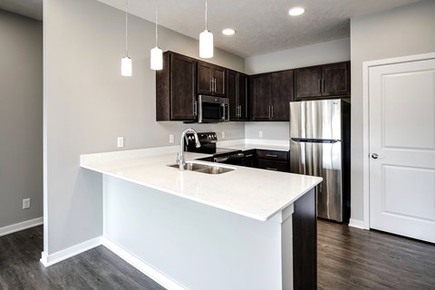 A kitchen with a white countertop and dark brown cabinets.