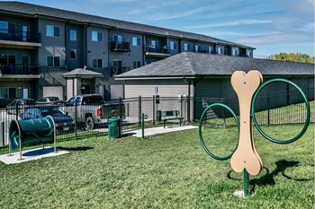 A dog park with a large dog sculpture in the foreground.