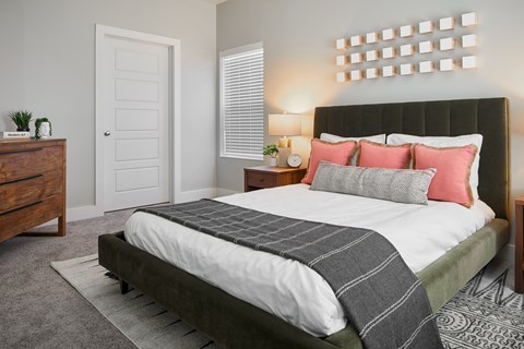 A bedroom with a large bed and a wooden dresser.