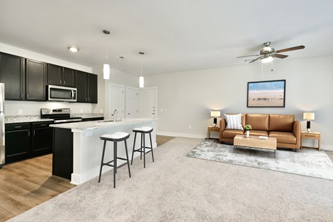 A modern kitchen with a bar area and a living room area with a couch.