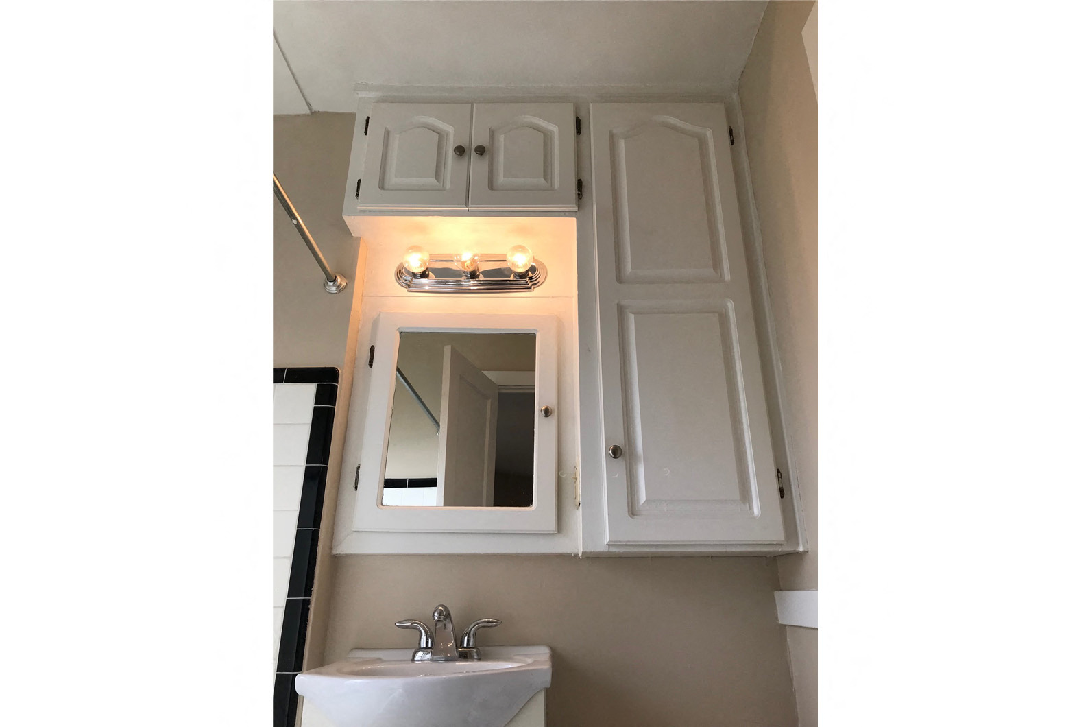 a bathroom with white cabinets and a sink and a mirror
