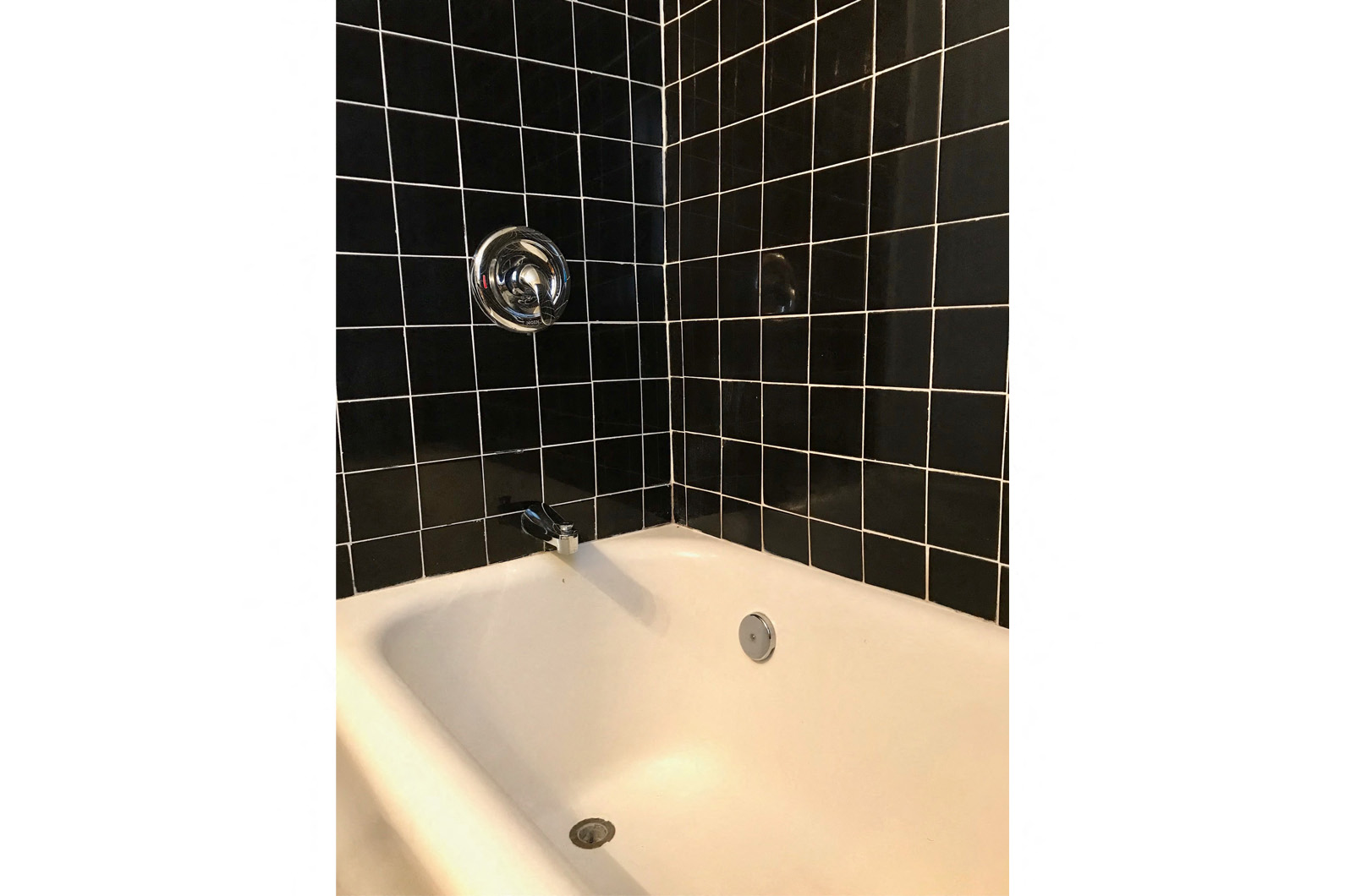 a black tiled bathroom with a tub and a faucet