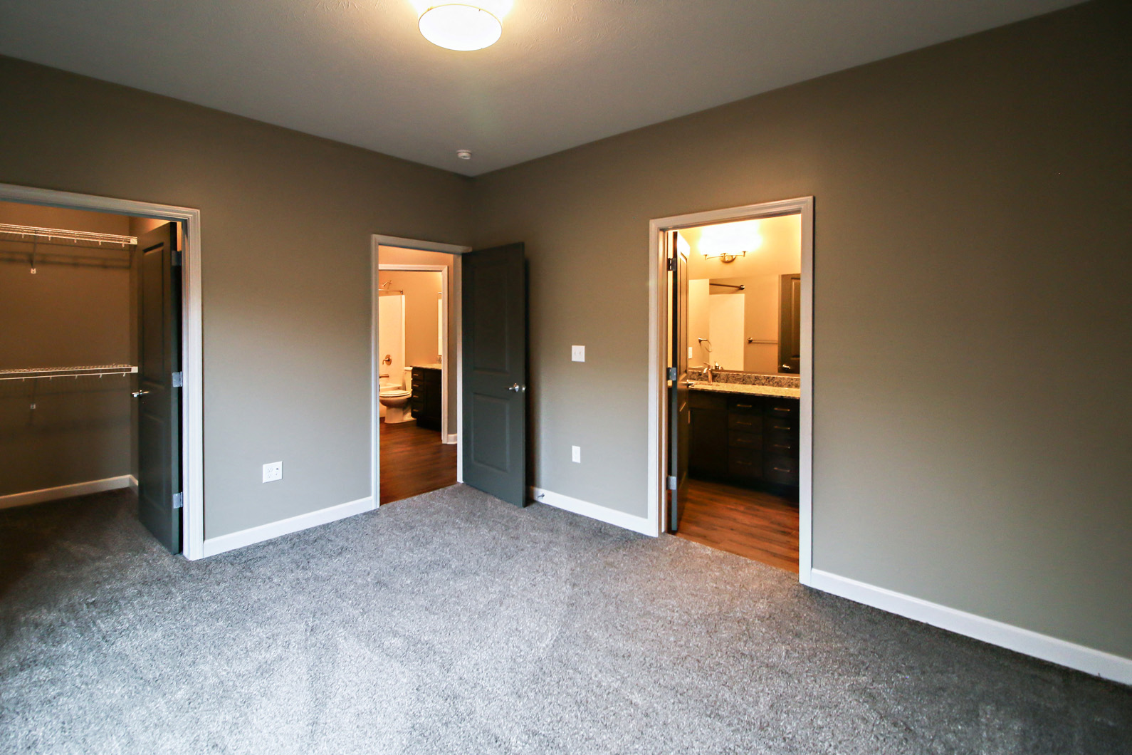 a living room with a carpeted floor and doors to a bedroom and a bathroom
