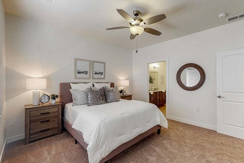 A bedroom with a bed, nightstand, and a ceiling fan.