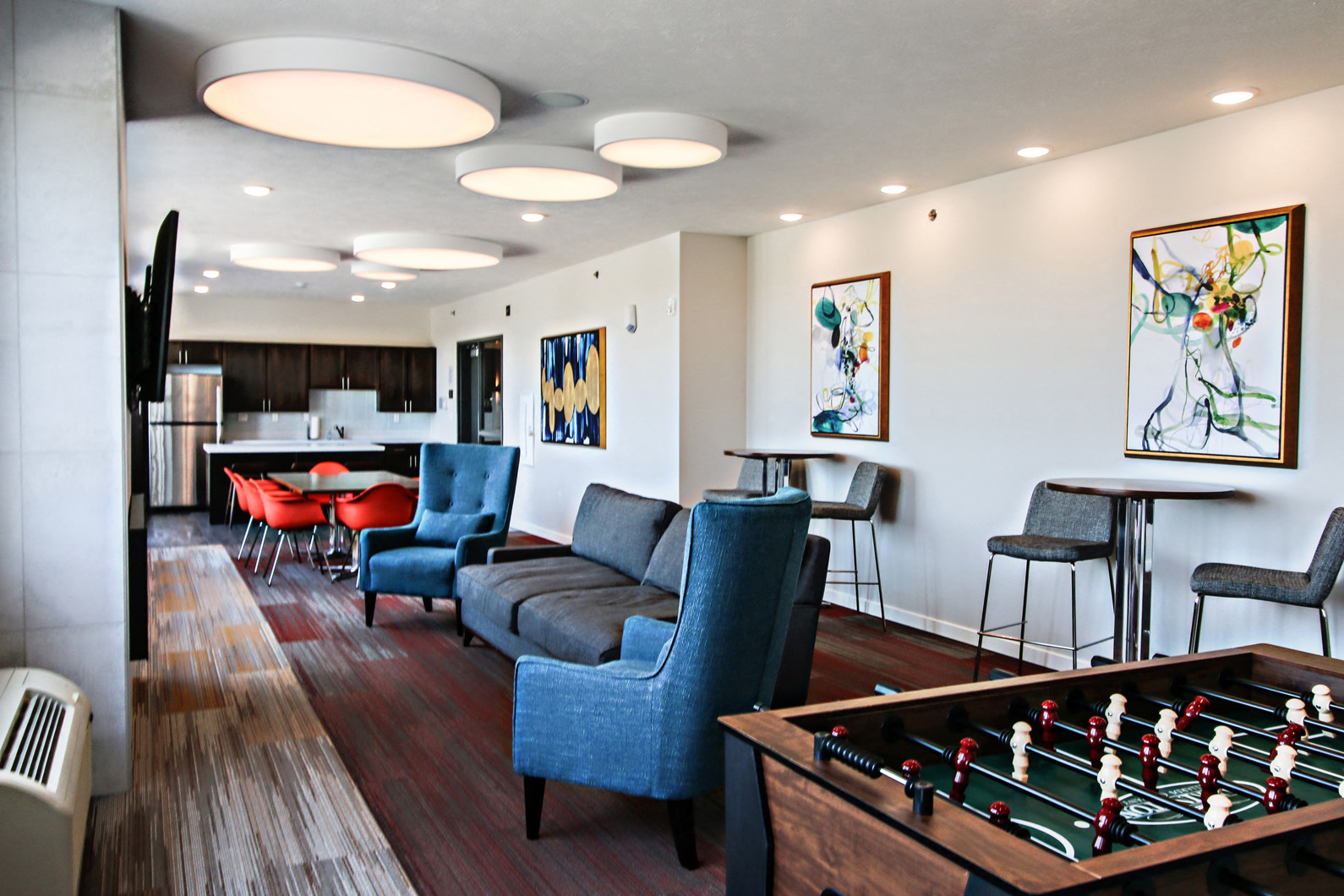 a living room with a foosball table and chairs and a kitchen
