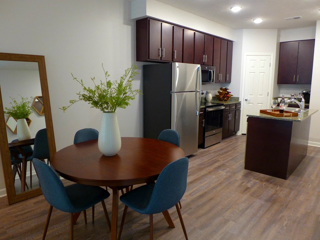 a dining room and kitchen with a table and chairs and a refrigerator