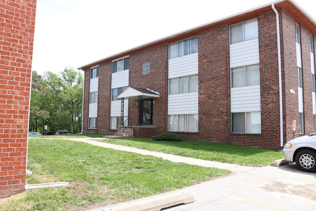a brick apartment building with a white car parked in front