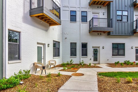 A white building with a balcony and a small garden in front.